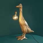 Duck Ducky Gold table lamp - luxury animal lamp with antique gold finish holding illuminated bulb in beak, perfect novelty lamp for modern living rooms