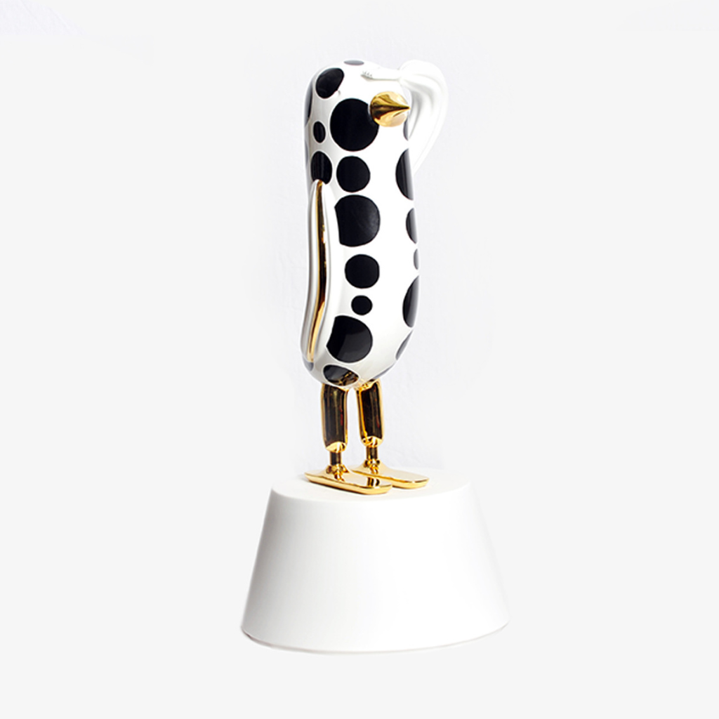 DOTS HOPE BIRD BY JAIME HAYON — white ceramic bird sculpture with black polka dots and 24-karat gold beak, legs, and feet on white pedestal. DOTS HOPE BIRD BY JAIME HAYON — white ceramic bird sculpture with black polka dots and 24-karat gold beak, legs, and feet on white pedestal.