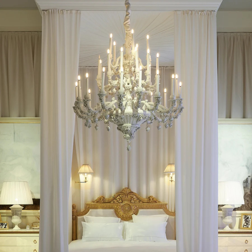 LOUIS XIV 36 LIGHT CHANDELIER WHITE in crisp white with floral motifs and candle-style arms, suspended in a luxury bedroom, handmade in Italy LOUIS XIV 36 LIGHT CHANDELIER WHITE in crisp white with floral motifs and candle-style arms, suspended in a luxury bedroom, handmade in Italy